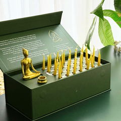 The 28-Day Meditation Kit open, showing the brass meditating figure holder and rows of yellow beeswax candles
