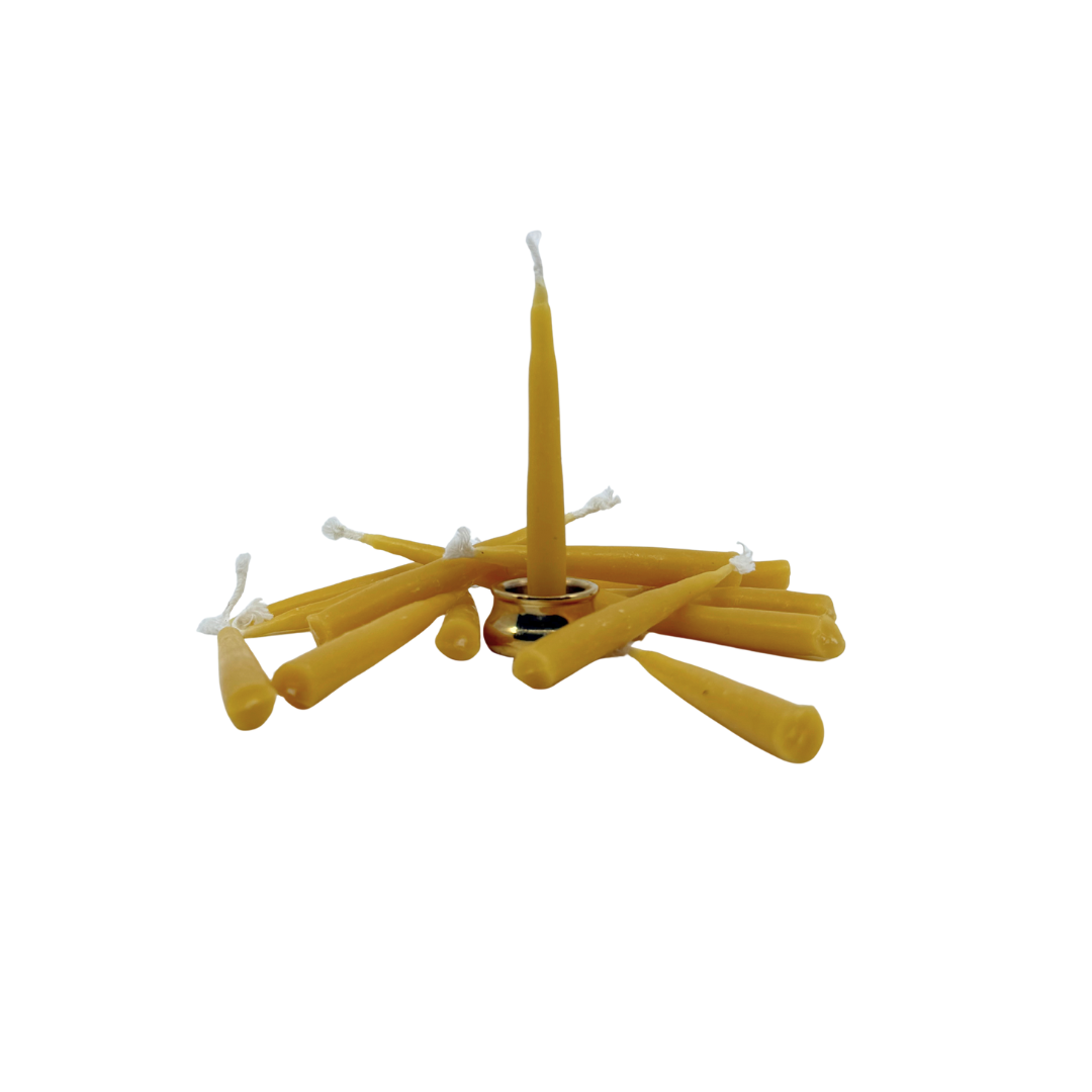 Brass meditating figure candle holder with beeswax candles fanned around it on a white background