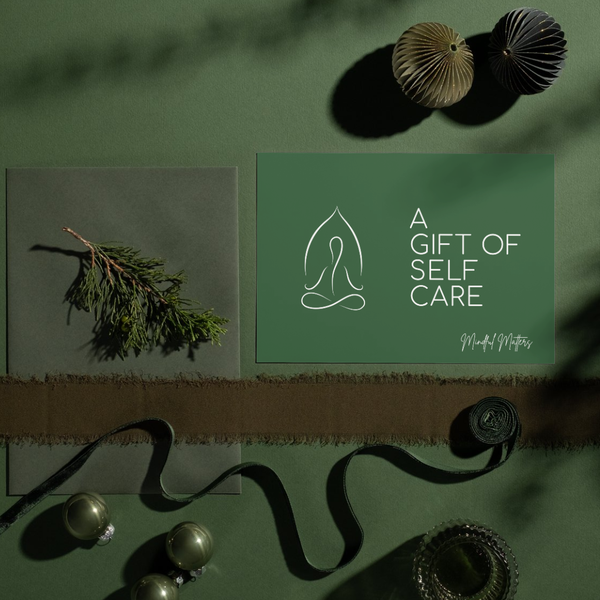 Mindful Matters Kit gift card in dark green reading 'A Gift of Self Care', styled with a eucalyptus sprig and shells